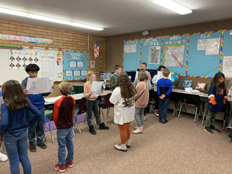 Students stand in front of another student to read a story