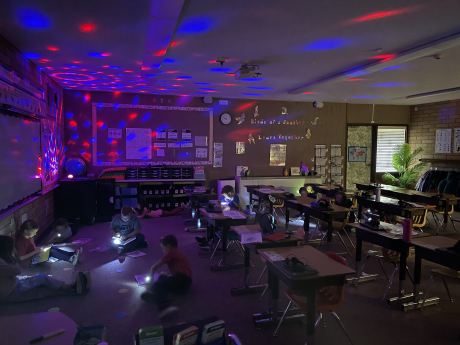 Students reading with flashlights in the classroom