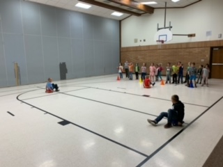 Students scooting on sliders for the relay race