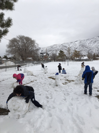 Students enjoying the snow and working together to build different snowmen