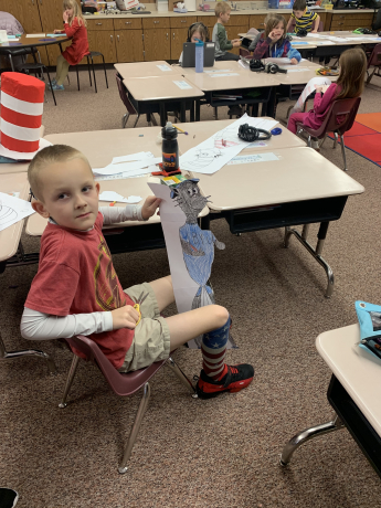 A student holds a picture he colored of The Cat in the Hat