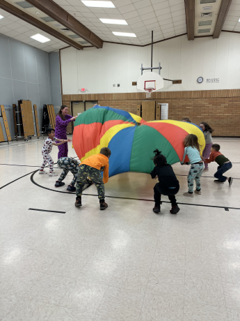 students playing with the parachute in the gym