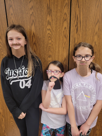 Girls show the beards they made for Mr. Richins