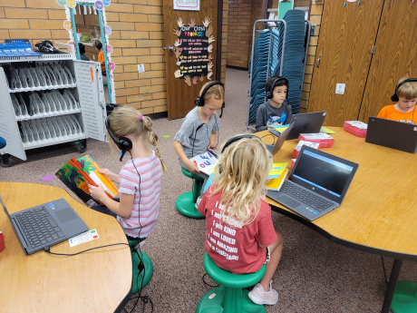 Students reading with the help of technology on chromebooks