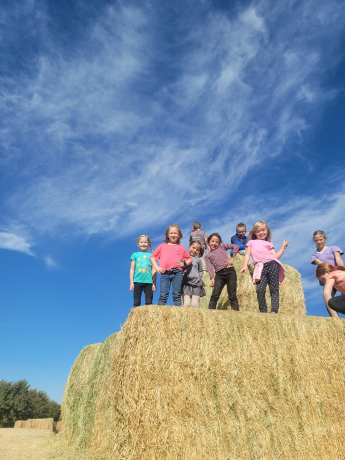 First graders post on the very top of a haystack