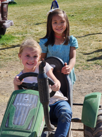 2 girls smile while playing on the tractor carts