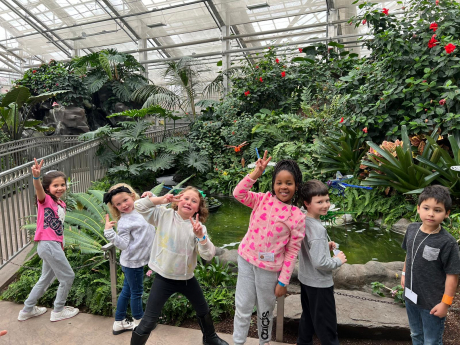 6 first graders pose in front of a garden
