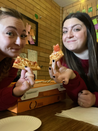 Mrs. McMullin and Mrs. Barnum pose with their pizza slices