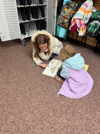 students leaning over their book together