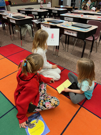 Students reading to their kindergarten buddy