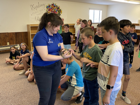 Students take turns petting a snake held by an aquarium employee