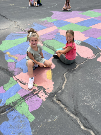 2 girls pose with their chalk drawings