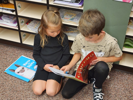 A 3rd grade boy reads to a kindergarten student