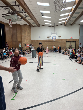 Students cheer as a 5th grade boy makes a basket